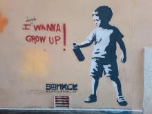 Street art: a small boy with an aerosol can and the text "I wanna grow up!"